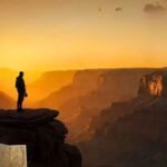 Explorer viewing Earth's Natural Wonders at sunrise with sustainable practices in a vast canyon landscape