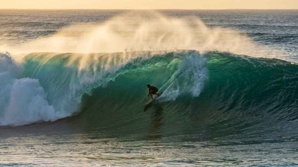 Surfer dropping into a massive Banzai Pipeline wave on Oahu's North Shore during Hawaii's big swell season