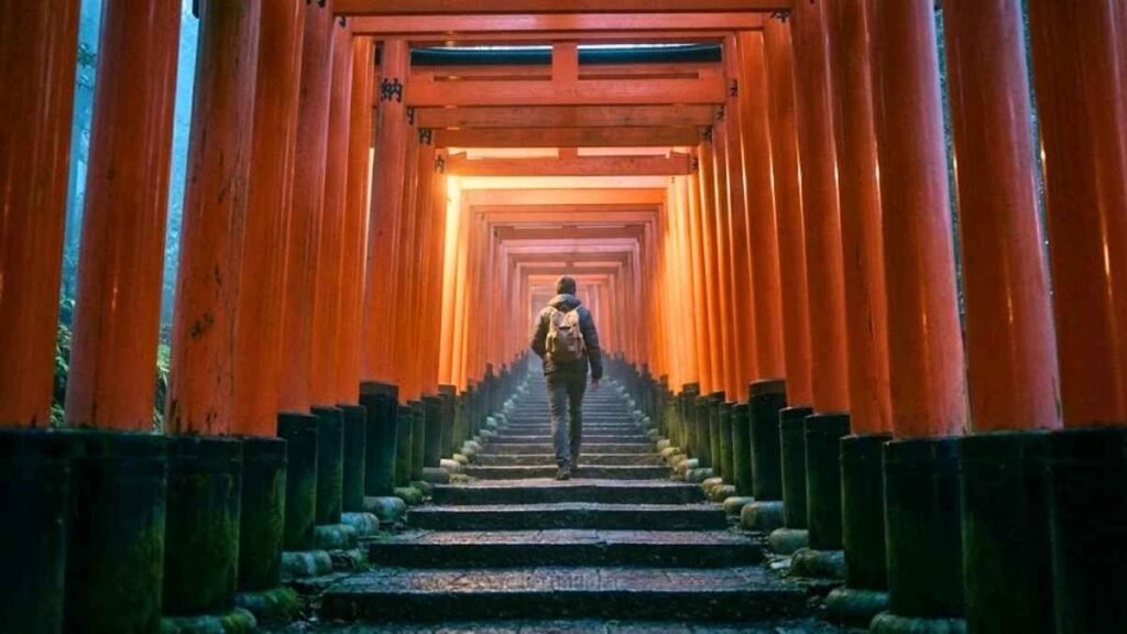 Solo hiker walking through the vermilion torii gates of Fushimi Inari shrine at dawn, Kyoto, best places in Japan