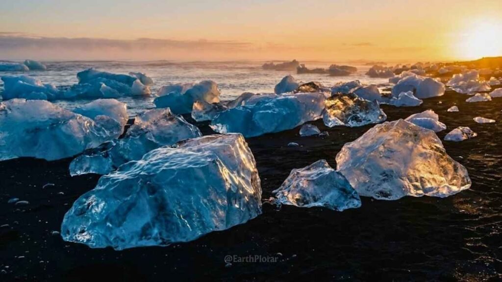 Translucent ice chunks from Jökulsárlón glacier lagoon glistening on Diamond Beach black sand at sunrise, Iceland destinations