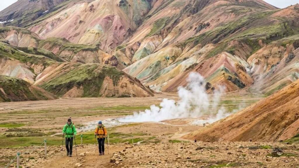 Hikers on the Laugavegur Trail with Landmannalaugar's multicoloured rhyolite mountains and geothermal steam, Iceland